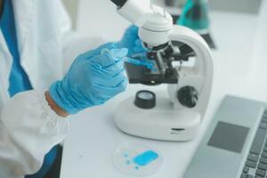 Health care researchers working in life science laboratory. Young female research scientist and senior male supervisor preparing and analyzing microscope slides in research lab. photo