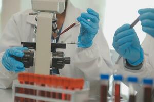 Health care researchers working in life science laboratory. Young female research scientist and senior male supervisor preparing and analyzing microscope slides in research lab. photo