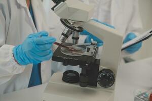 Health care researchers working in life science laboratory. Young female research scientist and senior male supervisor preparing and analyzing microscope slides in research lab. photo