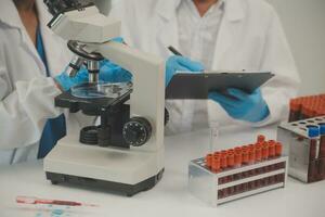 Health care researchers working in life science laboratory. Young female research scientist and senior male supervisor preparing and analyzing microscope slides in research lab. photo