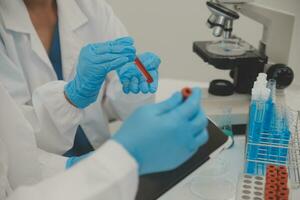 Health care researchers working in life science laboratory. Young female research scientist and senior male supervisor preparing and analyzing microscope slides in research lab. photo