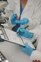 Health care researchers working in life science laboratory. Young female research scientist and senior male supervisor preparing and analyzing microscope slides in research lab. photo