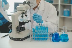 investigadores de atención médica que trabajan en el laboratorio de ciencias de la vida. joven científica investigadora y supervisora masculina senior preparando y analizando portaobjetos de microscopio en el laboratorio de investigación. foto