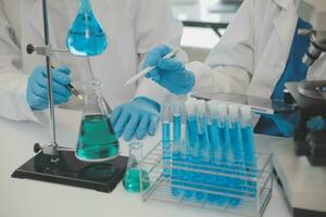 Health care researchers working in life science laboratory. Young female research scientist and senior male supervisor preparing and analyzing microscope slides in research lab. photo