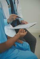 Close up of doctor sitting on bedside of male patient in hospital photo