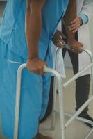 young asian physical therapist working with senior woman on walking with a walker photo