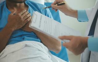 Close up of doctor sitting on bedside of male patient in hospital photo