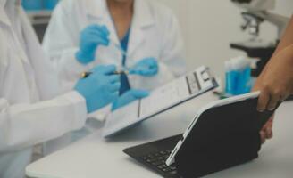 Health care researchers working in life science laboratory. Young female research scientist and senior male supervisor preparing and analyzing microscope slides in research lab. photo