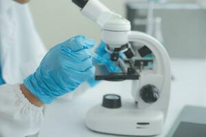 Health care researchers working in life science laboratory. Young female research scientist and senior male supervisor preparing and analyzing microscope slides in research lab. photo