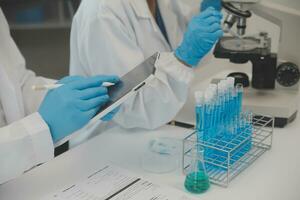 Health care researchers working in life science laboratory. Young female research scientist and senior male supervisor preparing and analyzing microscope slides in research lab. photo