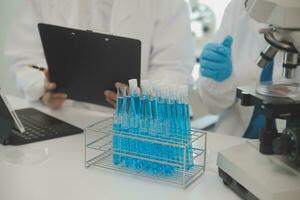 Health care researchers working in life science laboratory. Young female research scientist and senior male supervisor preparing and analyzing microscope slides in research lab. photo