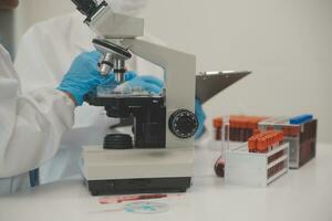 Health care researchers working in life science laboratory. Young female research scientist and senior male supervisor preparing and analyzing microscope slides in research lab. photo