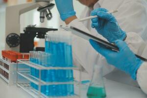 Health care researchers working in life science laboratory. Young female research scientist and senior male supervisor preparing and analyzing microscope slides in research lab. photo