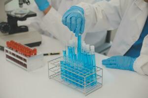 investigadores de atención médica que trabajan en el laboratorio de ciencias de la vida. joven científica investigadora y supervisora masculina senior preparando y analizando portaobjetos de microscopio en el laboratorio de investigación. foto