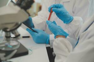 Health care researchers working in life science laboratory. Young female research scientist and senior male supervisor preparing and analyzing microscope slides in research lab. photo