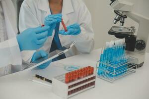 Health care researchers working in life science laboratory. Young female research scientist and senior male supervisor preparing and analyzing microscope slides in research lab. photo