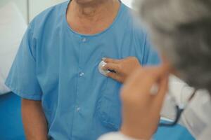 Close up of Female Doctor using stethoscope putting beat heart diagnose with patient in examination room at a hospital, check-up body, Medical and Health Care Concept. photo