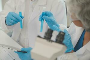 Health care researchers working in life science laboratory. Young female research scientist and senior male supervisor preparing and analyzing microscope slides in research lab. photo