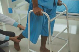 young asian physical therapist working with senior woman on walking with a walker photo