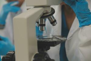 Health care researchers working in life science laboratory. Young female research scientist and senior male supervisor preparing and analyzing microscope slides in research lab. photo