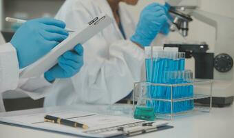 Health care researchers working in life science laboratory. Young female research scientist and senior male supervisor preparing and analyzing microscope slides in research lab. photo