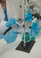 Health care researchers working in life science laboratory. Young female research scientist and senior male supervisor preparing and analyzing microscope slides in research lab. photo