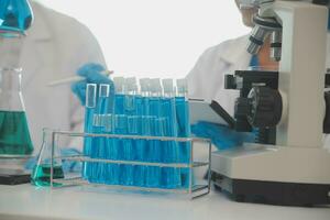 Health care researchers working in life science laboratory. Young female research scientist and senior male supervisor preparing and analyzing microscope slides in research lab. photo