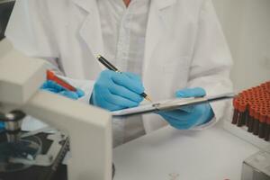 investigadores de atención médica que trabajan en el laboratorio de ciencias de la vida. joven científica investigadora y supervisora masculina senior preparando y analizando portaobjetos de microscopio en el laboratorio de investigación. foto