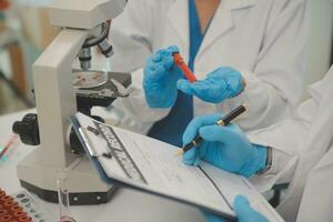 investigadores de atención médica que trabajan en el laboratorio de ciencias de la vida. joven científica investigadora y supervisora masculina senior preparando y analizando portaobjetos de microscopio en el laboratorio de investigación. foto