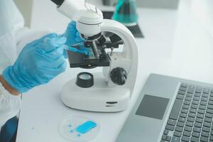 Health care researchers working in life science laboratory. Young female research scientist and senior male supervisor preparing and analyzing microscope slides in research lab. photo