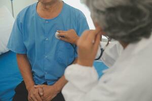 Close up of Female Doctor using stethoscope putting beat heart diagnose with patient in examination room at a hospital, check-up body, Medical and Health Care Concept. photo