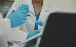Health care researchers working in life science laboratory. Young female research scientist and senior male supervisor preparing and analyzing microscope slides in research lab. photo