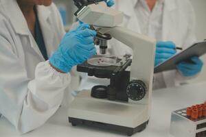 Health care researchers working in life science laboratory. Young female research scientist and senior male supervisor preparing and analyzing microscope slides in research lab. photo