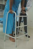 young asian physical therapist working with senior woman on walking with a walker photo