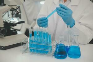 Health care researchers working in life science laboratory. Young female research scientist and senior male supervisor preparing and analyzing microscope slides in research lab. photo