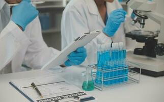 Health care researchers working in life science laboratory. Young female research scientist and senior male supervisor preparing and analyzing microscope slides in research lab. photo