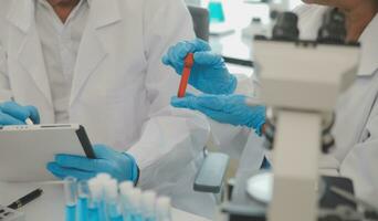 Health care researchers working in life science laboratory. Young female research scientist and senior male supervisor preparing and analyzing microscope slides in research lab. photo