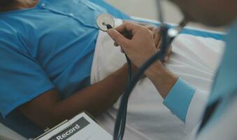 Close up of doctor sitting on bedside of male patient in hospital photo