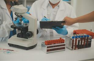 Health care researchers working in life science laboratory. Young female research scientist and senior male supervisor preparing and analyzing microscope slides in research lab. photo