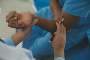 Close up of doctor sitting on bedside of male patient in hospital photo