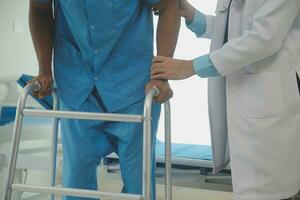 young asian physical therapist working with senior woman on walking with a walker photo