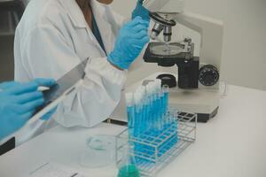 Health care researchers working in life science laboratory. Young female research scientist and senior male supervisor preparing and analyzing microscope slides in research lab. photo