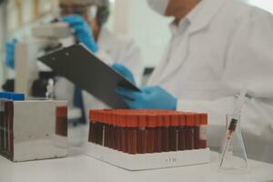 Health care researchers working in life science laboratory. Young female research scientist and senior male supervisor preparing and analyzing microscope slides in research lab. photo