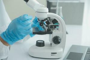 Health care researchers working in life science laboratory. Young female research scientist and senior male supervisor preparing and analyzing microscope slides in research lab. photo