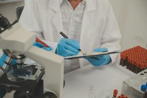 Health care researchers working in life science laboratory. Young female research scientist and senior male supervisor preparing and analyzing microscope slides in research lab. photo