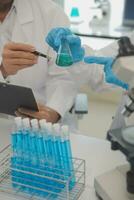 Health care researchers working in life science laboratory. Young female research scientist and senior male supervisor preparing and analyzing microscope slides in research lab. photo