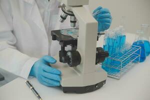 Health care researchers working in life science laboratory. Young female research scientist and senior male supervisor preparing and analyzing microscope slides in research lab. photo