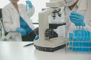 Health care researchers working in life science laboratory. Young female research scientist and senior male supervisor preparing and analyzing microscope slides in research lab. photo