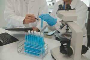 Health care researchers working in life science laboratory. Young female research scientist and senior male supervisor preparing and analyzing microscope slides in research lab. photo