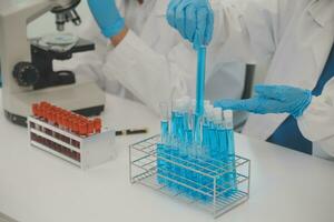 investigadores de atención médica que trabajan en el laboratorio de ciencias de la vida. joven científica investigadora y supervisora masculina senior preparando y analizando portaobjetos de microscopio en el laboratorio de investigación. foto